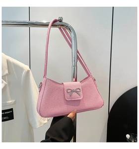 Detalle del bolso de cuero rosa texturizado con una hebilla decorativa de lazo plateado
