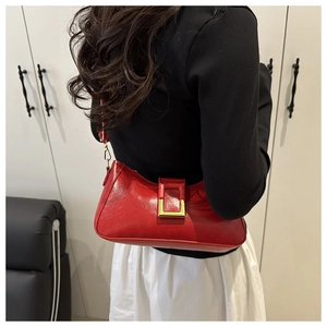 Gros plan sur un sac d'épaule en cuir brillant rouge avec une boucle carrée dorée élégante
