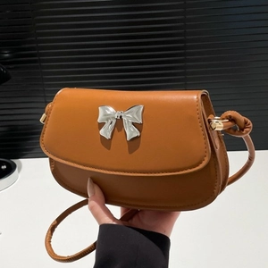 Caramel faux leather crossbody bag with silver bow accent and saddle flap design