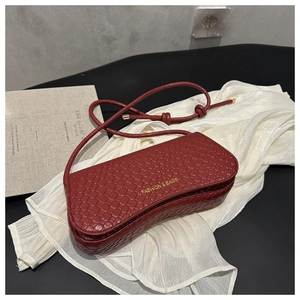 Detail of burgundy crocodile-embossed leather handbag with gold fashion lettering