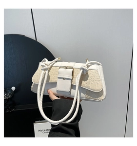 Close-up of white shoulder bag featuring crocodile texture flap and knotted strap detail