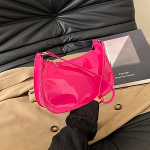 Bright pink patent leather underarm bag in minimalist crescent shape with glossy finish