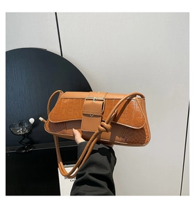 Detail of brown crocodile pattern shoulder bag featuring a decorative metal buckle