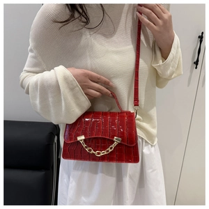 Detail of red crocodile texture small square bag with decorative gold metal chain