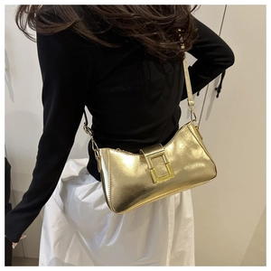 Gros plan du sac baguette doré métallisé avec une grande boucle et une finition brillante