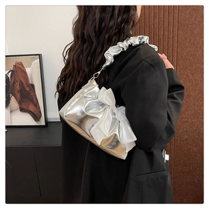 Detail of silver metallic PU leather bag featuring a large organza bow and ruffled strap