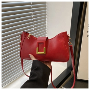 Détail du sac à épaule en similicuir rouge avec boucle dorée et fermeture éclair