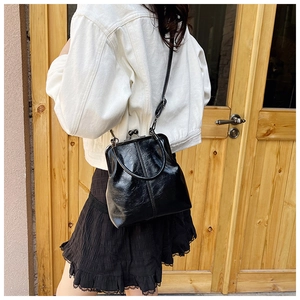 Detail of black glossy doctor bag with metal frame clasp and vertical stitch texture