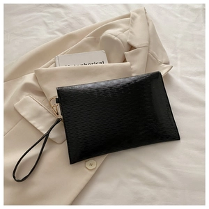 Detail of black envelope clutch featuring wave texture and light gold hardware accents