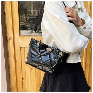 Detail of black quilted leather shoulder bag with gold twist lock and chain handle