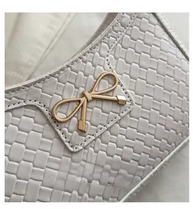 Détail du sac en cuir tressé avec une boucle en métal doré en forme de nœud et lumière douce