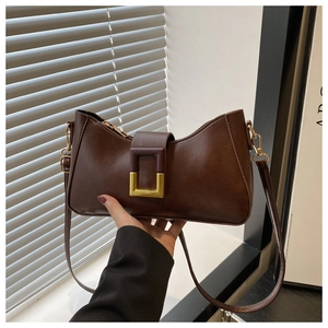 Détail du sac à bandoulière marron foncé avec boucle dorée élégante et texture cuir fin
