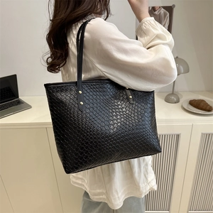 Fashion woven black leather tote bag with gold stud detail on model in office setting