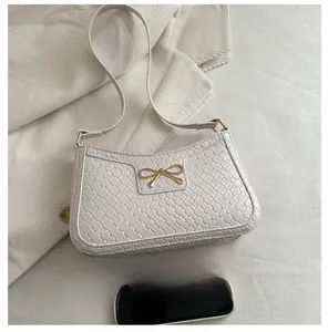 Détail du sac à bandoulière blanc à motif tressé avec boucle en métal doré en nœud