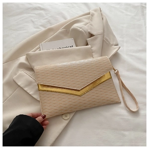 Detail of beige textured envelope clutch with gold V-metal trim and wrist strap