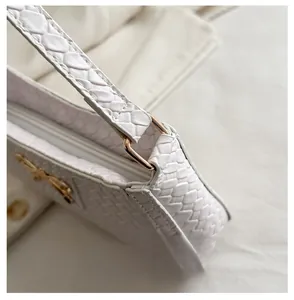 Gros plan sur la texture serpent blanc et le nœud doré de ce sac à bandoulière chic