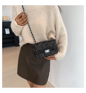 Détail d'un sac bandoulière en tweed noir avec fermoir rotatif argenté et bandoulière chaîne
