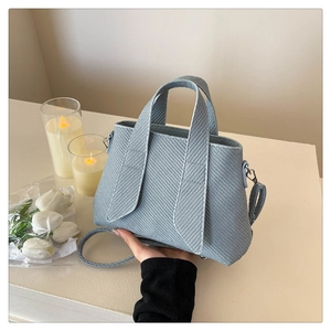 Detail of light blue striped tote bag with elegant woven texture and slender shoulder strap