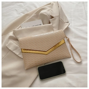 Detail of beige envelope clutch bag featuring ripple texture and gold V-shaped metal hardware