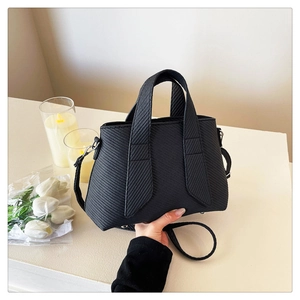 Close-up of black crossbody tote bag with detailed diagonal woven texture and strap