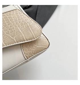 Detail of cream leather shoulder bag with beige crocodile texture and fine stitching