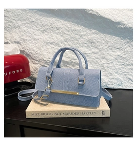 Detailed texture of light blue denim fabric handbag with elegant golden metal closure