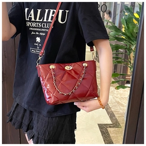Close-up of deep red quilted glossy shoulder bag with metal chain and twist lock