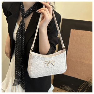 Détail du sac à bandoulière tissé blanc avec emblème papillon doré sur le devant