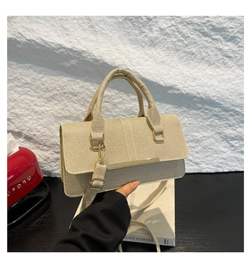 Detail of beige woven handbag featuring elegant gold metal trim and reinforced top handles