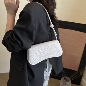 White woven texture baguette shoulder bag with gold lettering shown on model in black blazer