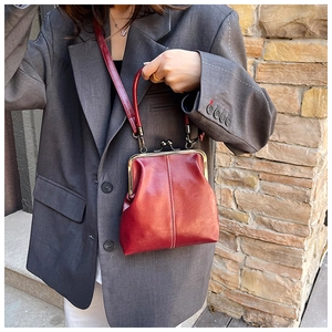 Detail of vintage red leather doctor bag with gold kiss-lock closure and vertical stitching