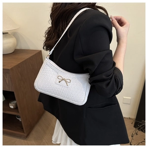 Détail du sac bandoulière blanc tressé avec boucle papillon dorée et bandoulière chic