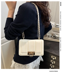 Détail du sac à bandoulière blanc avec coutures verticales et fermoir doré chic
