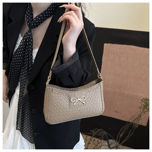 Gros plan du sac à main kaki tressé avec boucle de nœud en métal doré et bandoulière fine