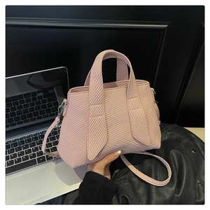 Close-up of light pink tote bag with diagonal striped texture and silver hardware