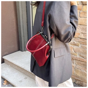 Side view of a vintage red leather doctor bag with white stitching and silver clasp closure