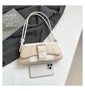 Detail view of cream crocodile textured bag showing size relative to a smartphone
