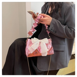 Detail of pink metallic crossbody bag featuring a large white organza bow and chain strap