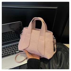 Detail of pink striped tote bag with dual handles and silver hooks in urban setting