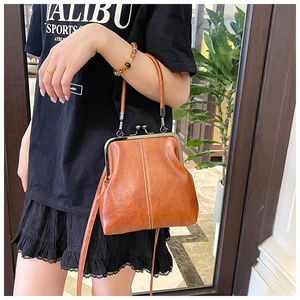 Brown vintage kiss-lock doctor bag with wax leather texture shown on model in daily use