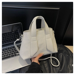 Detailed view of white woven texture handbag with wide handle and detachable strap