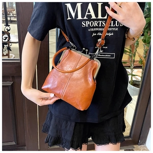 Detail view of a vintage brown leather bag with metal clasp and elegant handle