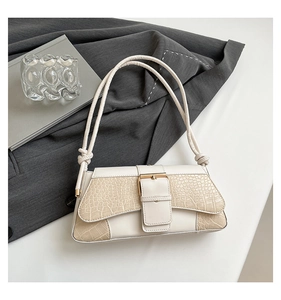 Overhead view of a creamy white crocodile-embossed shoulder bag with a metal buckle detail
