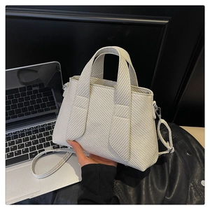Detail of cream woven tote bag showing fabric texture, silver hardware and detachable strap