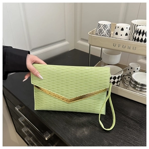 Detail showing wavy textured green envelope clutch bag with V-shaped gold metal trim edge