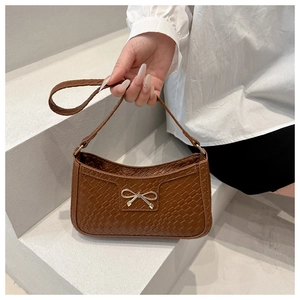 Détail d'un sac hobo marron tissé avec un nœud doré en métal et une courte bandoulière