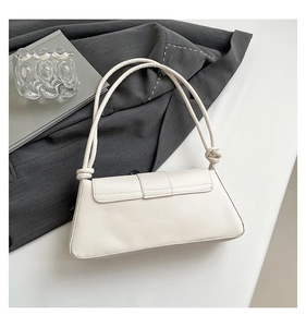 Detail of cream faux leather baguette bag with knotted strap and minimalist rectangular design