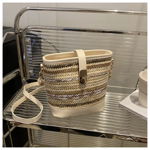 Detail of woven straw bucket bag with cream leather trim and gold twist lock closure