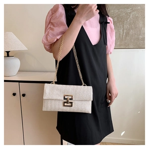 Detail of cream woven square bag with gold chain strap and geometric metal buckle clasp