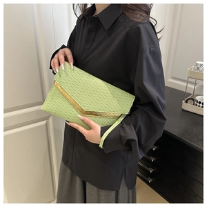 Detail of light green envelope clutch with wavy texture and gold V-shaped metal trim